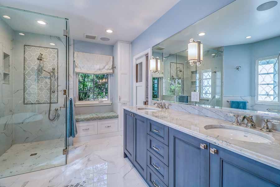 A bathroom with two sinks , a walk in shower and a large mirror.
