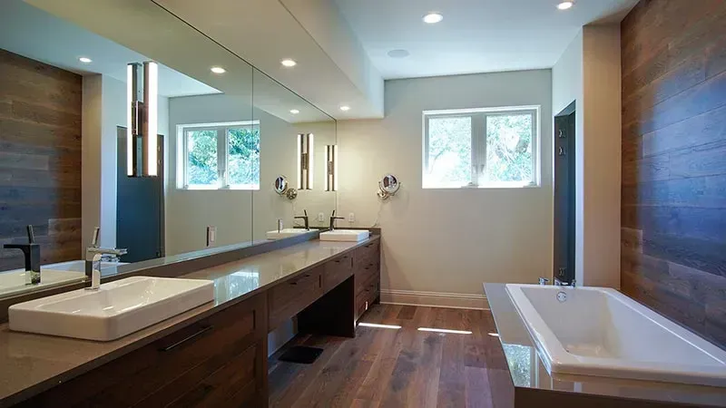 A bathroom with two sinks , a tub and a large mirror.