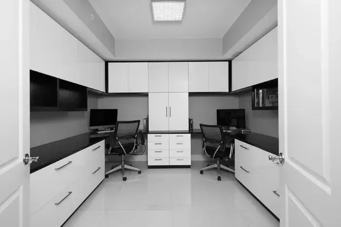 A black and white photo of an office with two desks and chairs