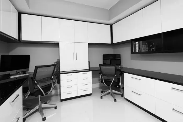 A black and white photo of a home office with two desks and chairs