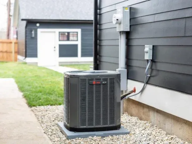 An air conditioner is sitting on the side of a house.
