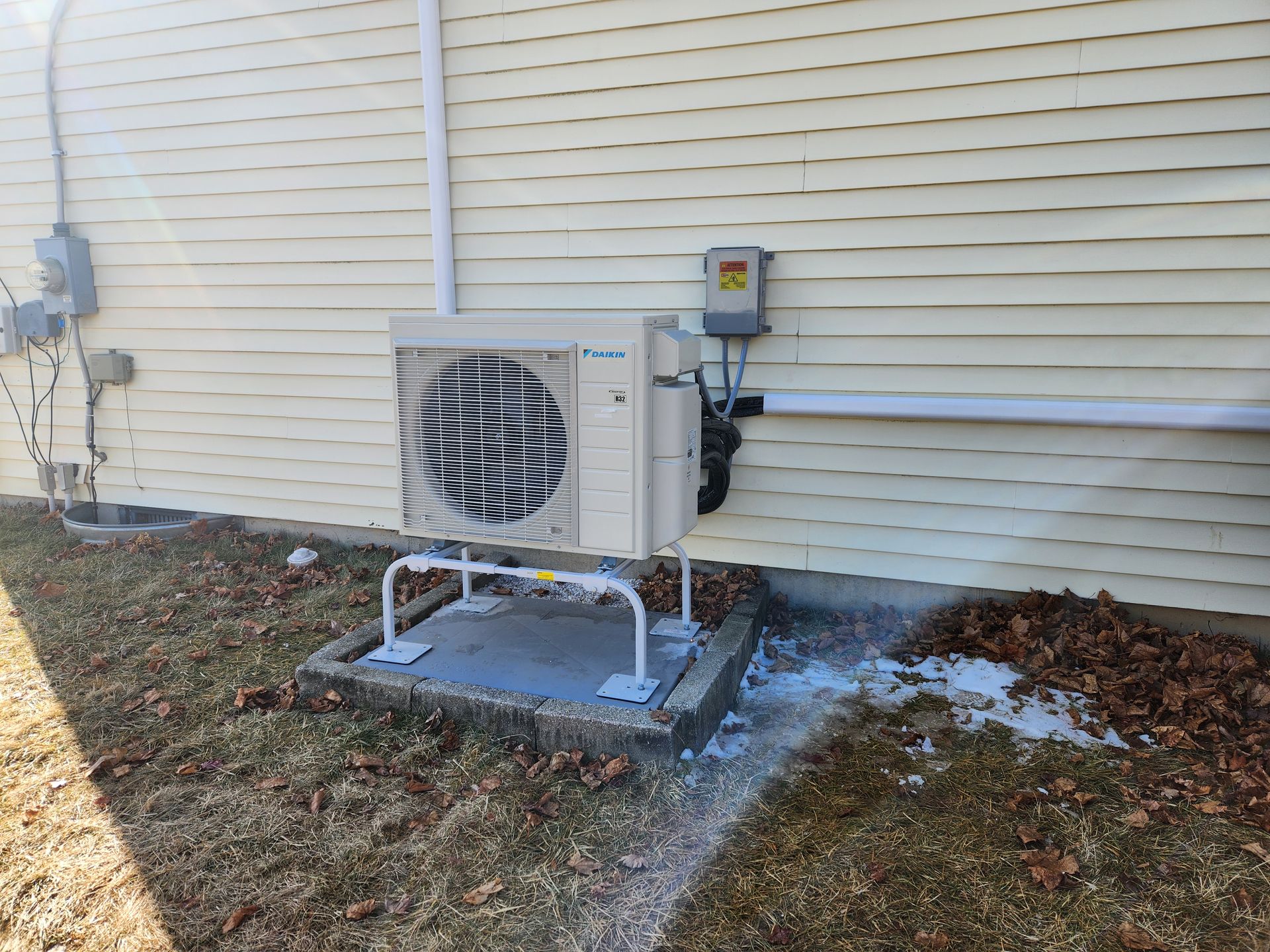 A white air conditioner is sitting on the side of a house.