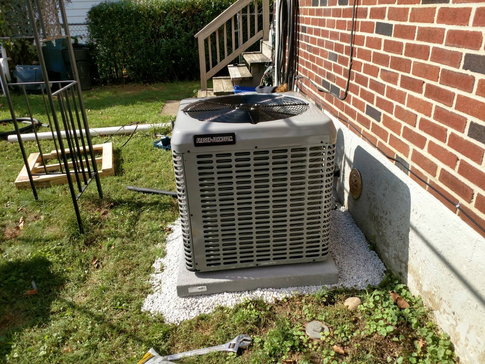 An air conditioner is sitting on the side of a brick house.