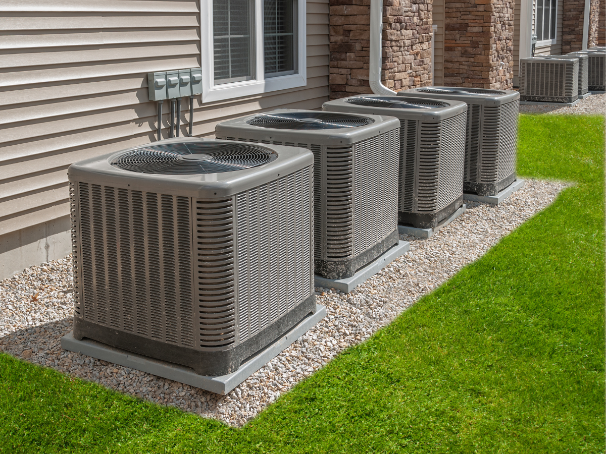 A row of air conditioners are sitting in front of a house. A row of air conditioners are sitting in front of a house.