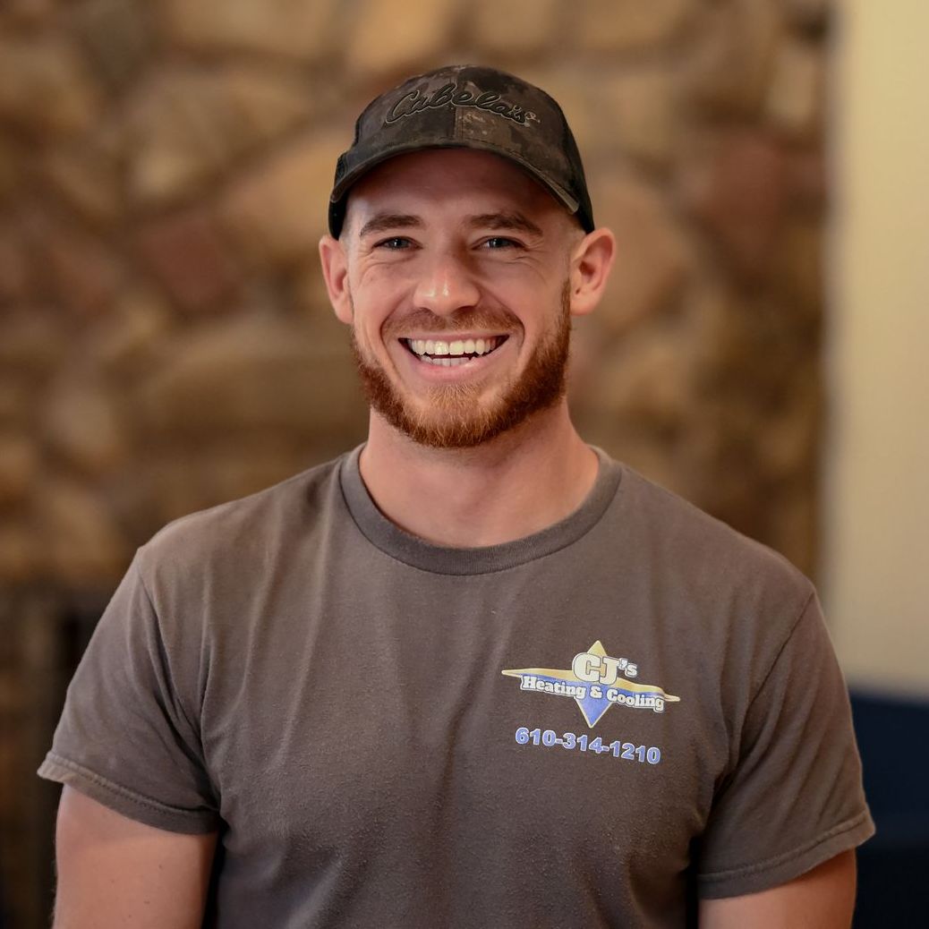 A man wearing a black hoodie and a beanie stands in front of a van that says heating and cooling