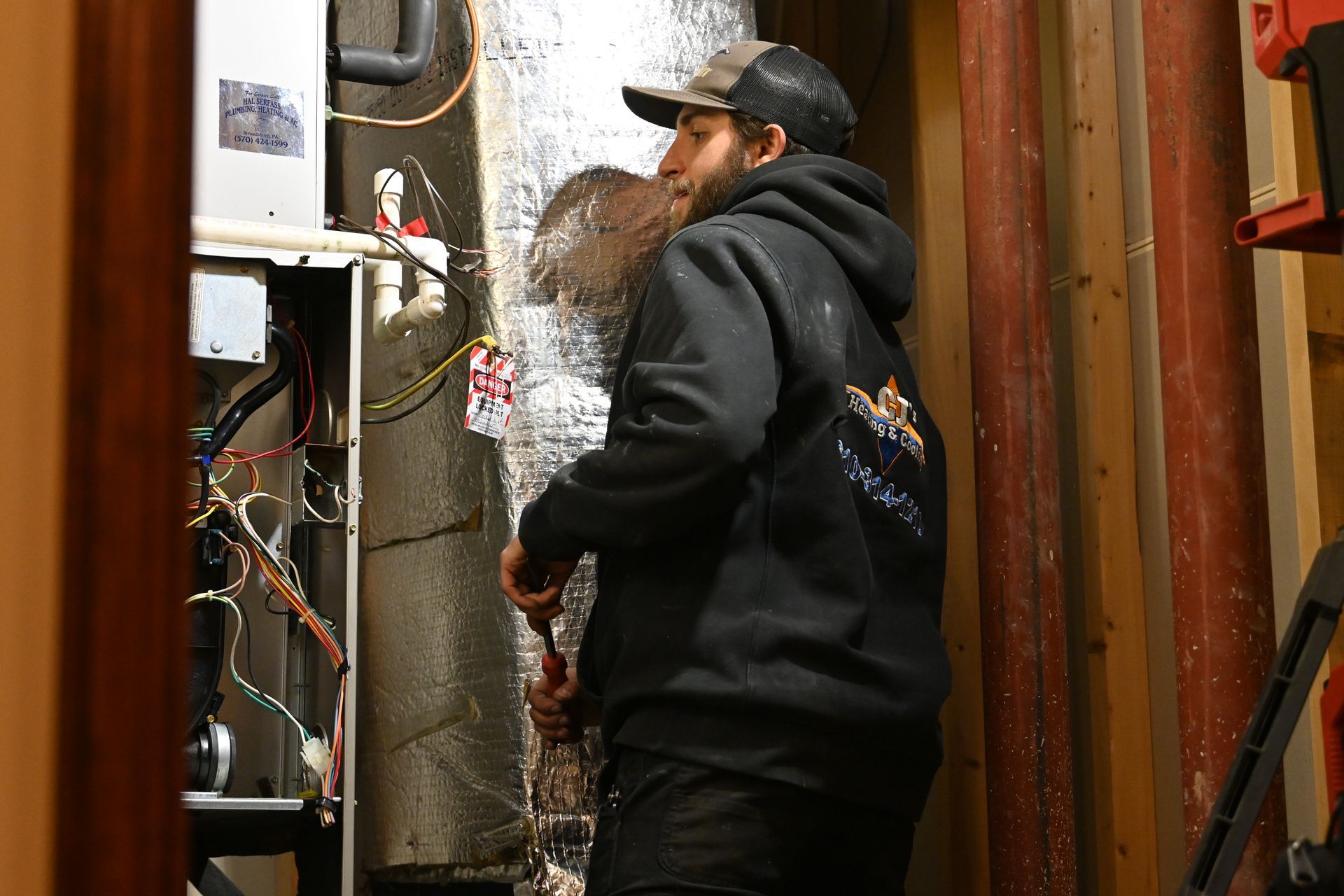 A man is working on an air conditioner in a basement.