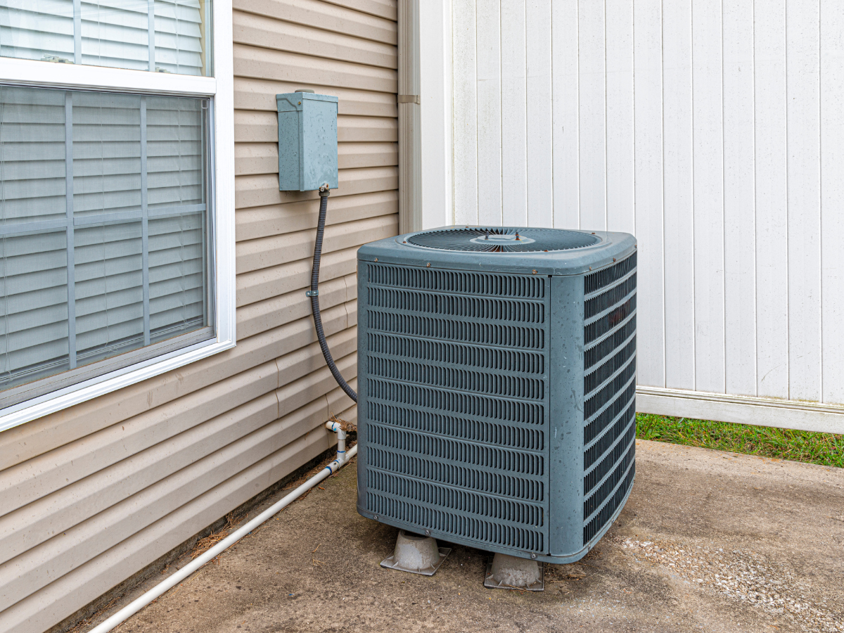 An air conditioner is sitting on the side of a house next to a window. An air conditioner is sitting on the side of a house next to a window.