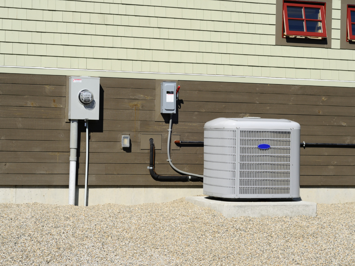 An air conditioner is mounted on the side of a house
