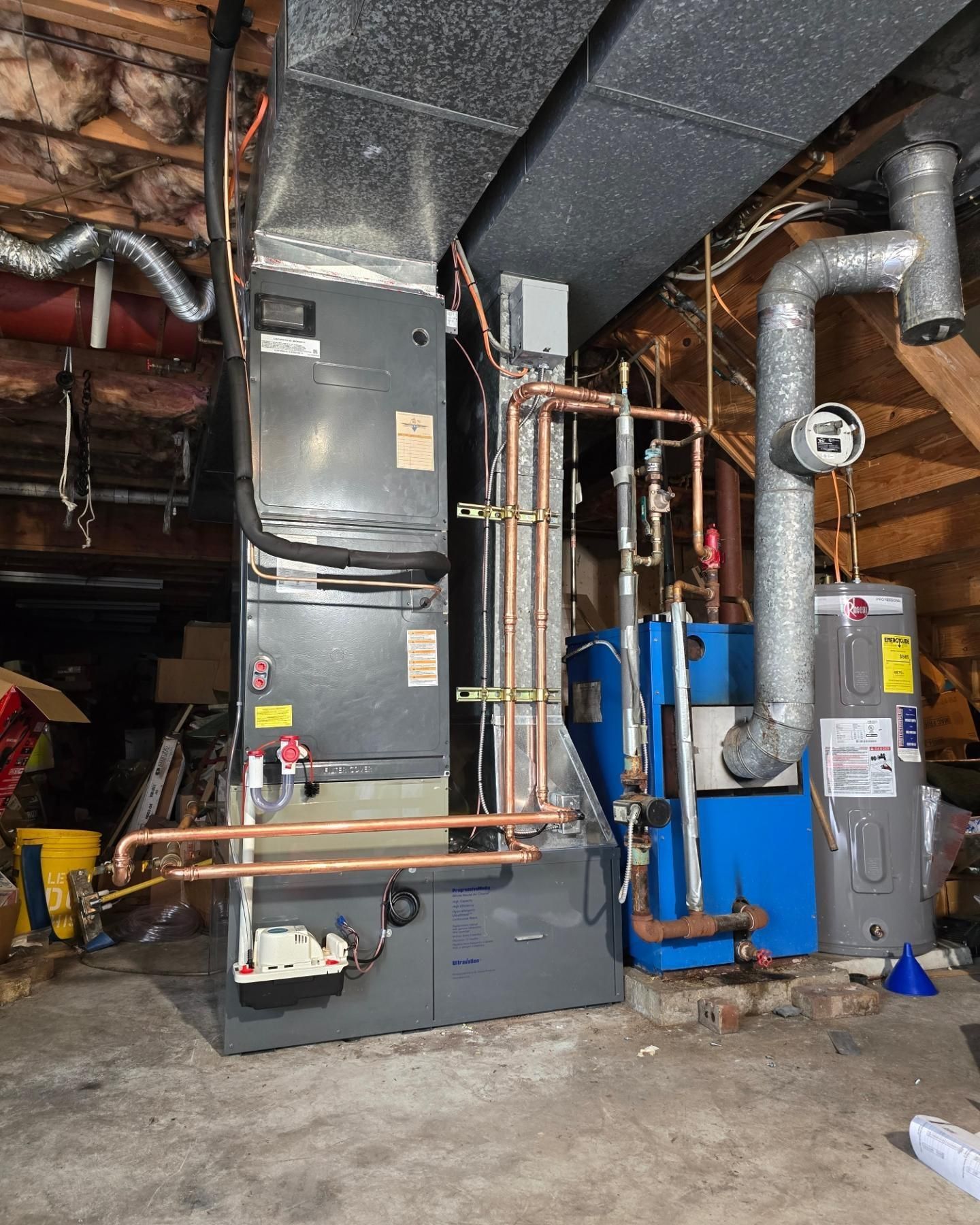 A boiler and a water heater are in a basement.