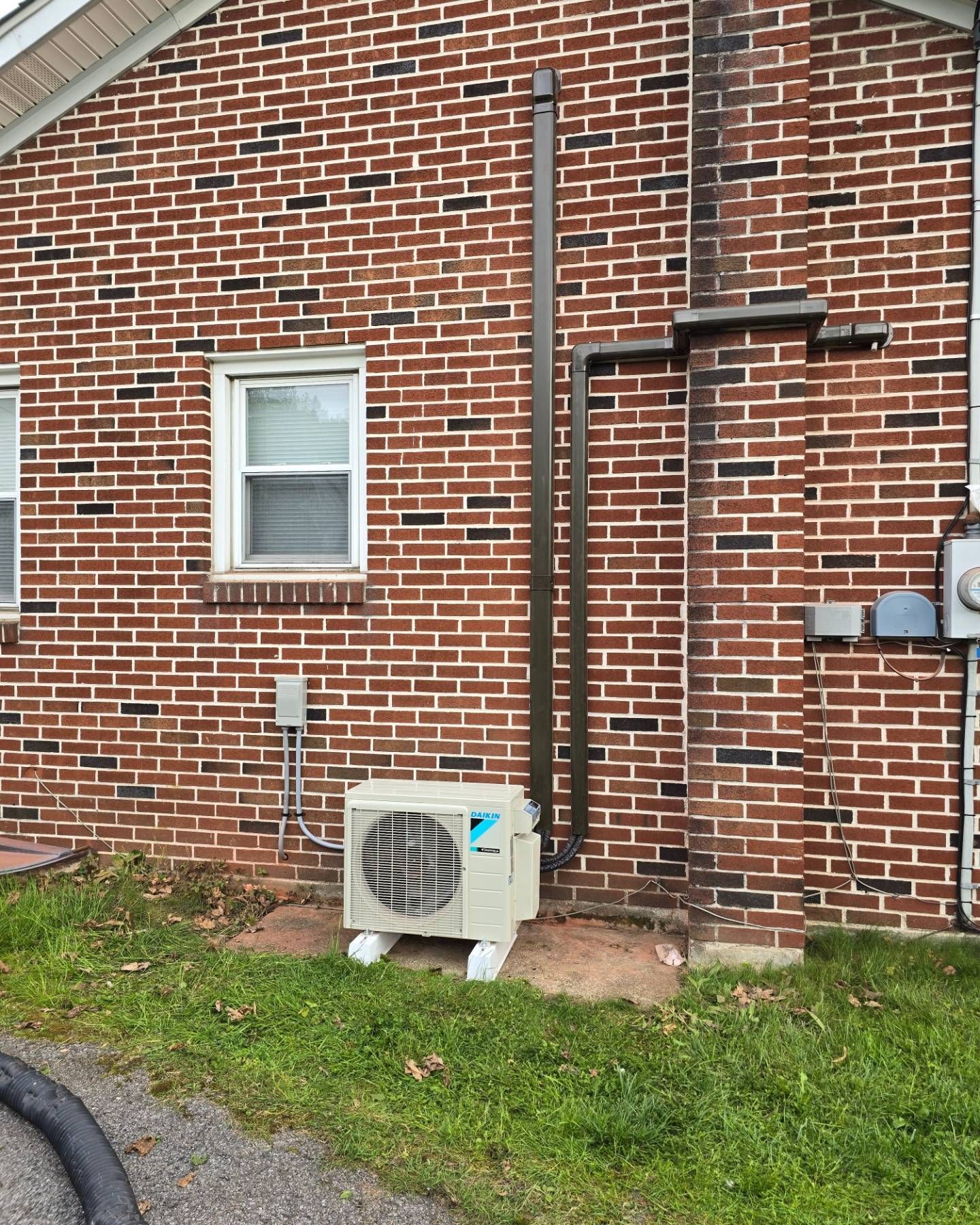 A brick house with a white air conditioner on the side of it.