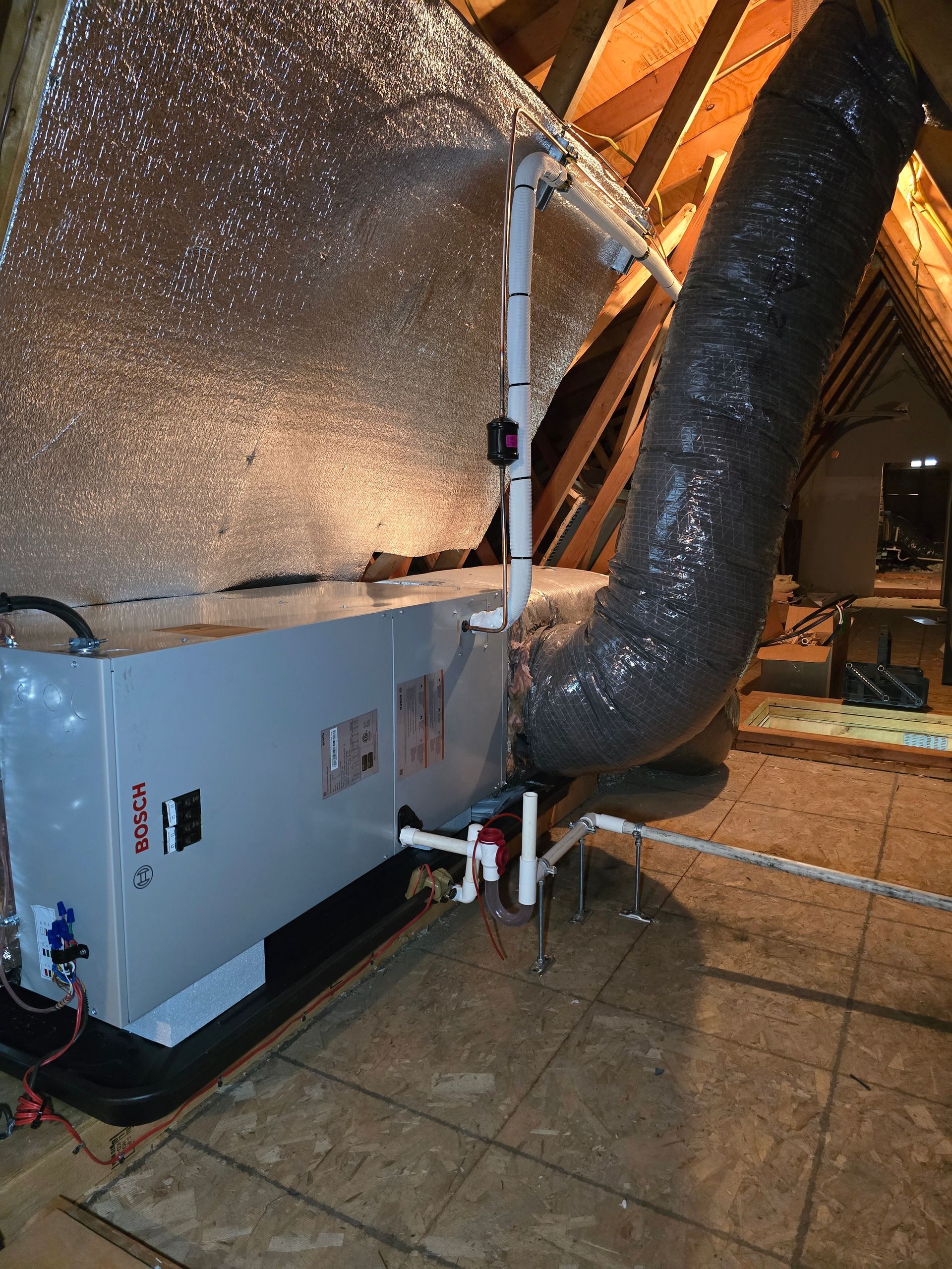 An air conditioner is being installed in an attic with a large hose coming out of it.