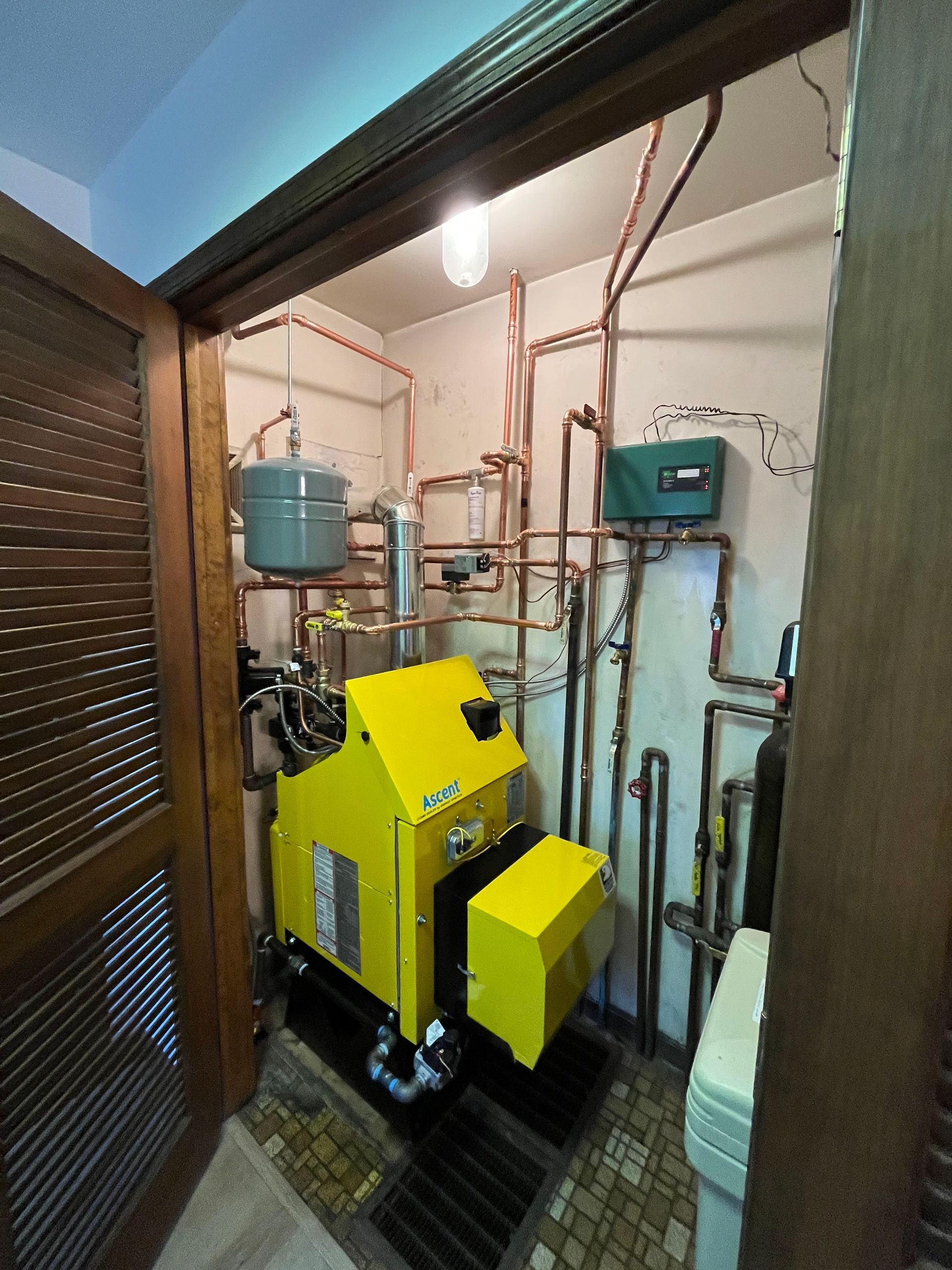 A yellow machine is sitting in a room with a lot of pipes.