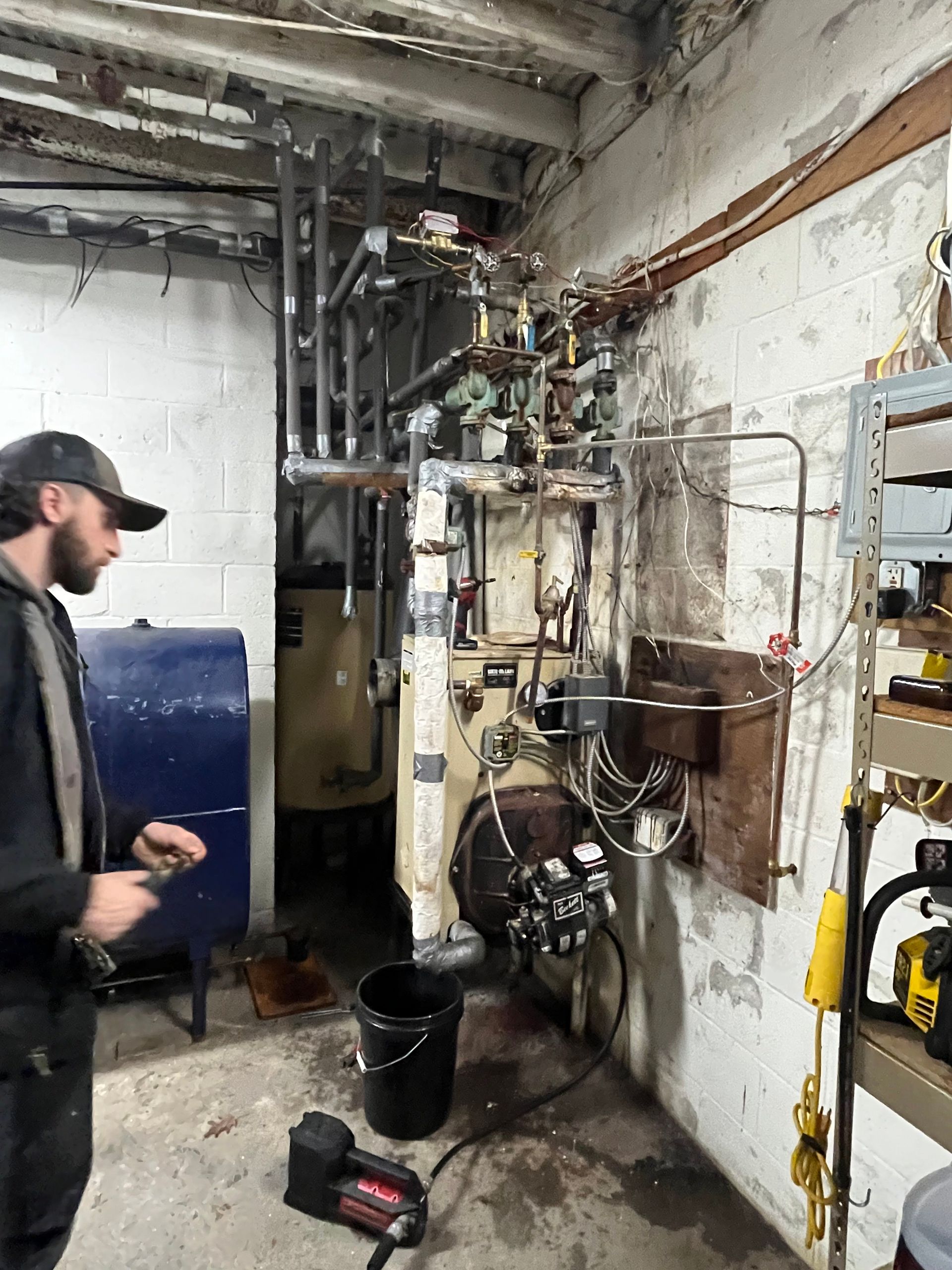 A man is standing in a room with a boiler and pipes.