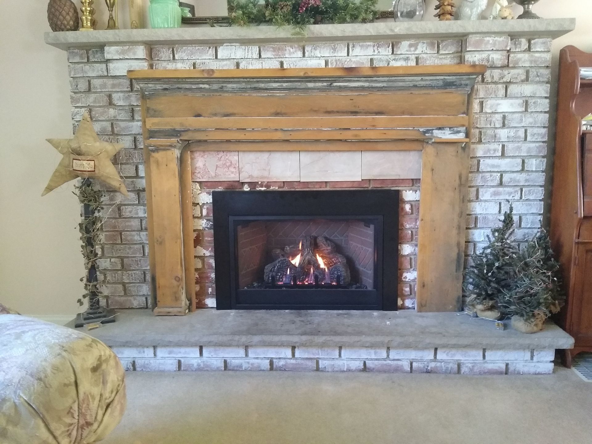 A living room with a brick fireplace and a wooden mantle