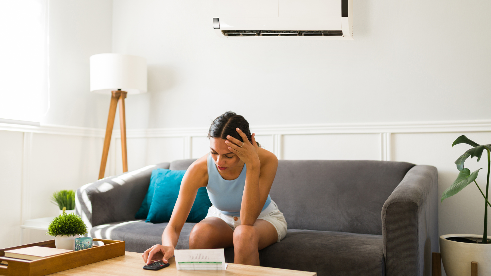 A woman is sitting on a couch in a living room looking at her phone.