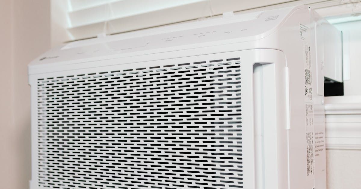 A white air conditioner is hanging from the ceiling next to a window.