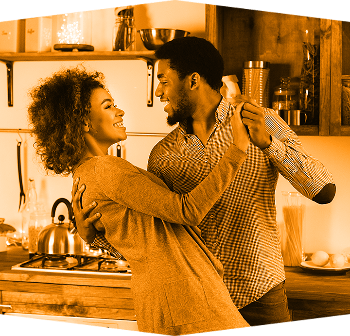 A man and a woman are dancing in a kitchen