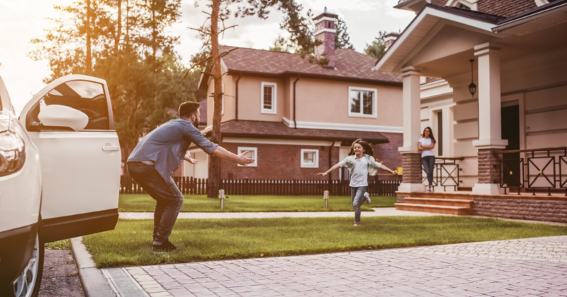 child running in front yard towards dad next to car