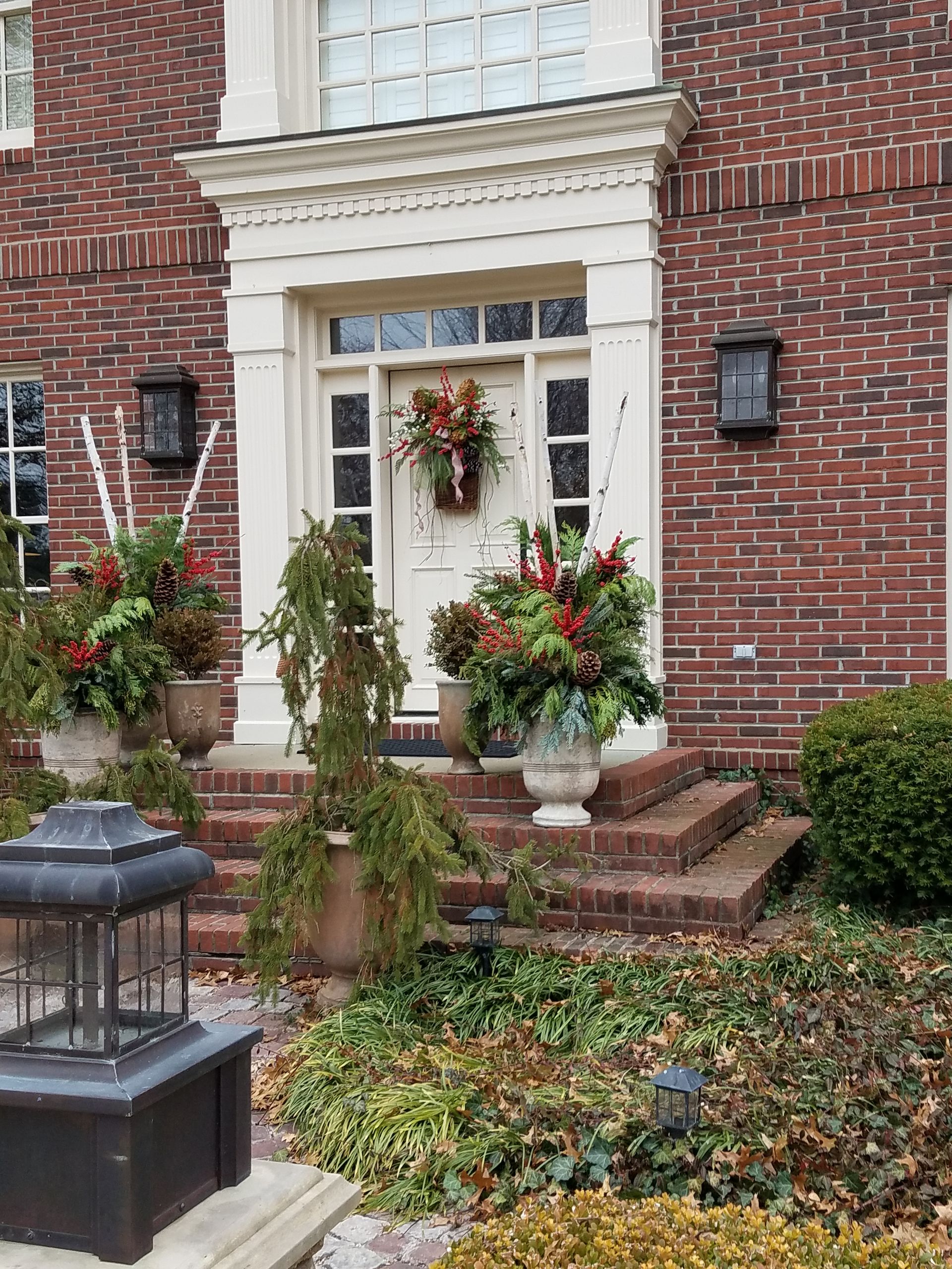 A Brick House with a White Door Decorated for Christmas  — Jasper, IN — Green Thumb Landscaping and Garden Center 