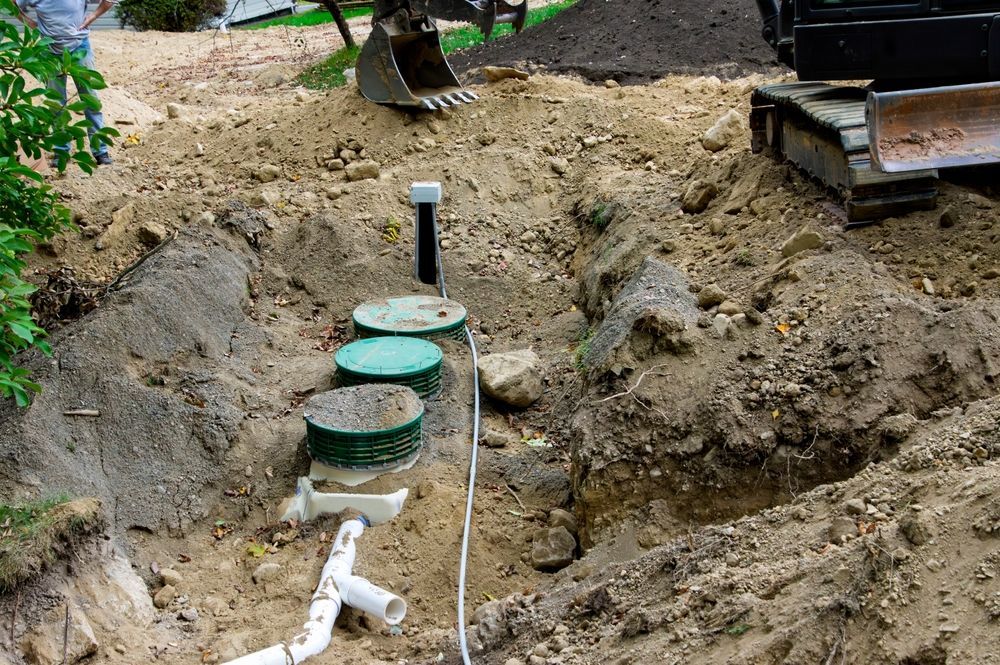 Excavation site with three green utility lids, exposed pipes, and a dug-out dirt trench