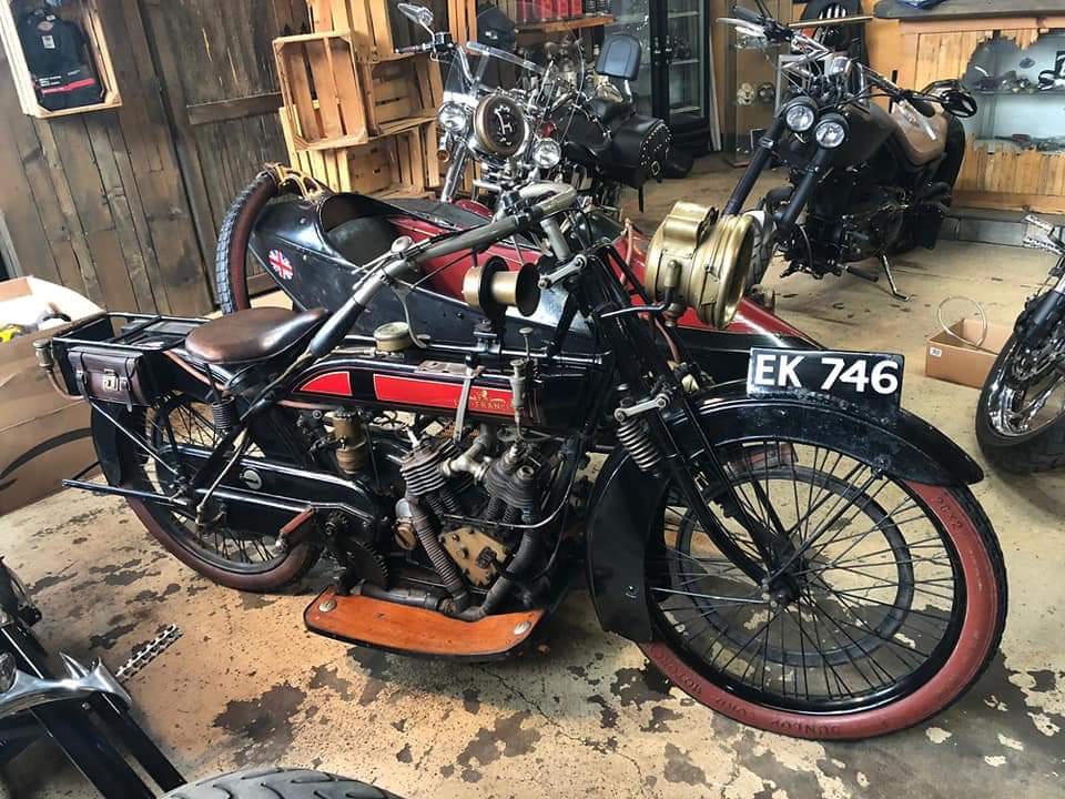 A row of old motorcycles are parked in a garage.