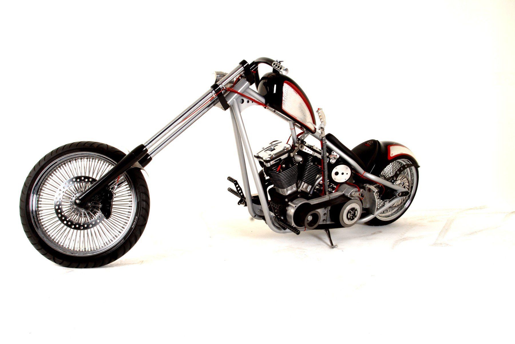 A chopper motorcycle is sitting on a white surface.