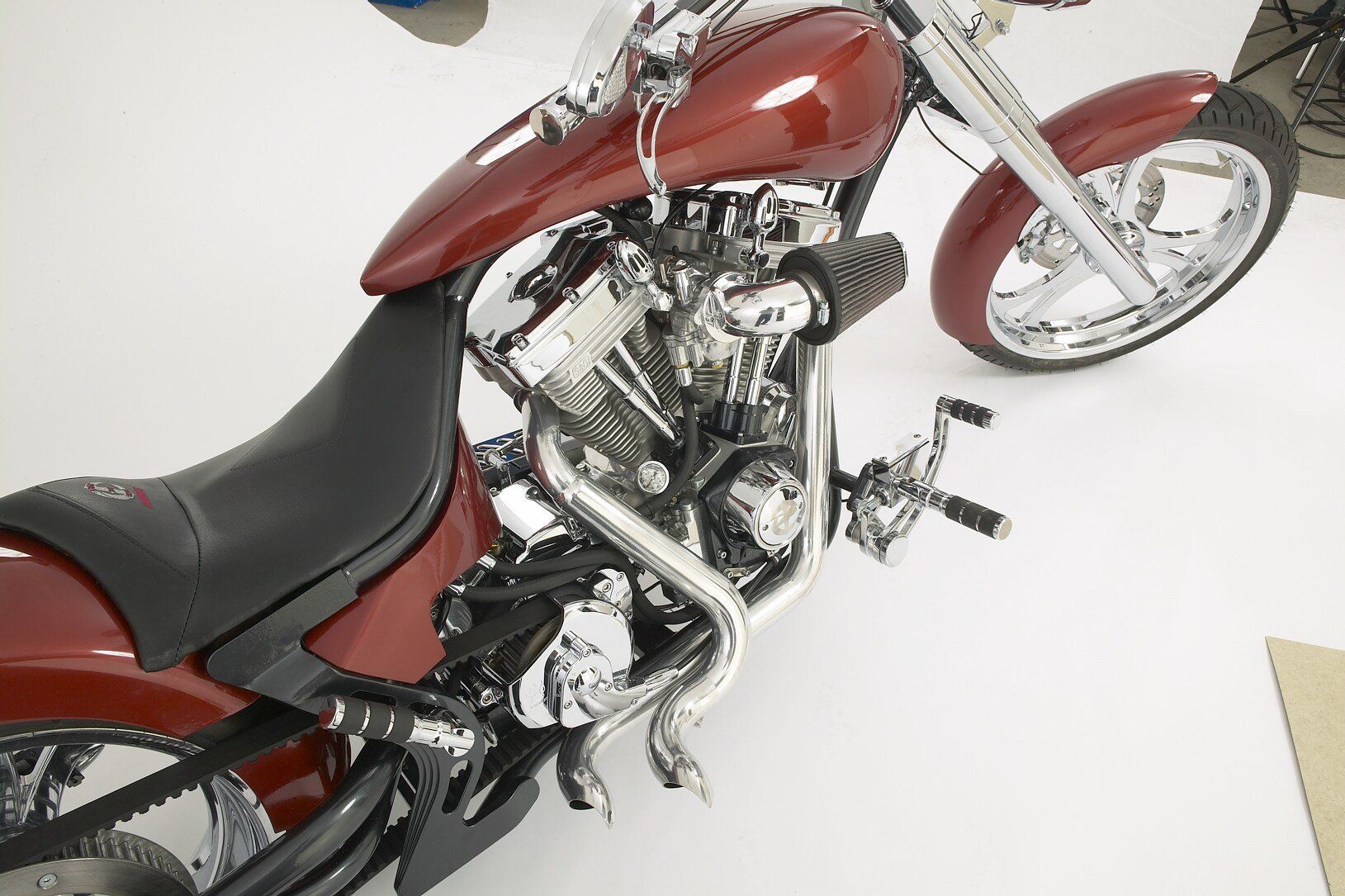 A red motorcycle with a black seat sits on a white surface