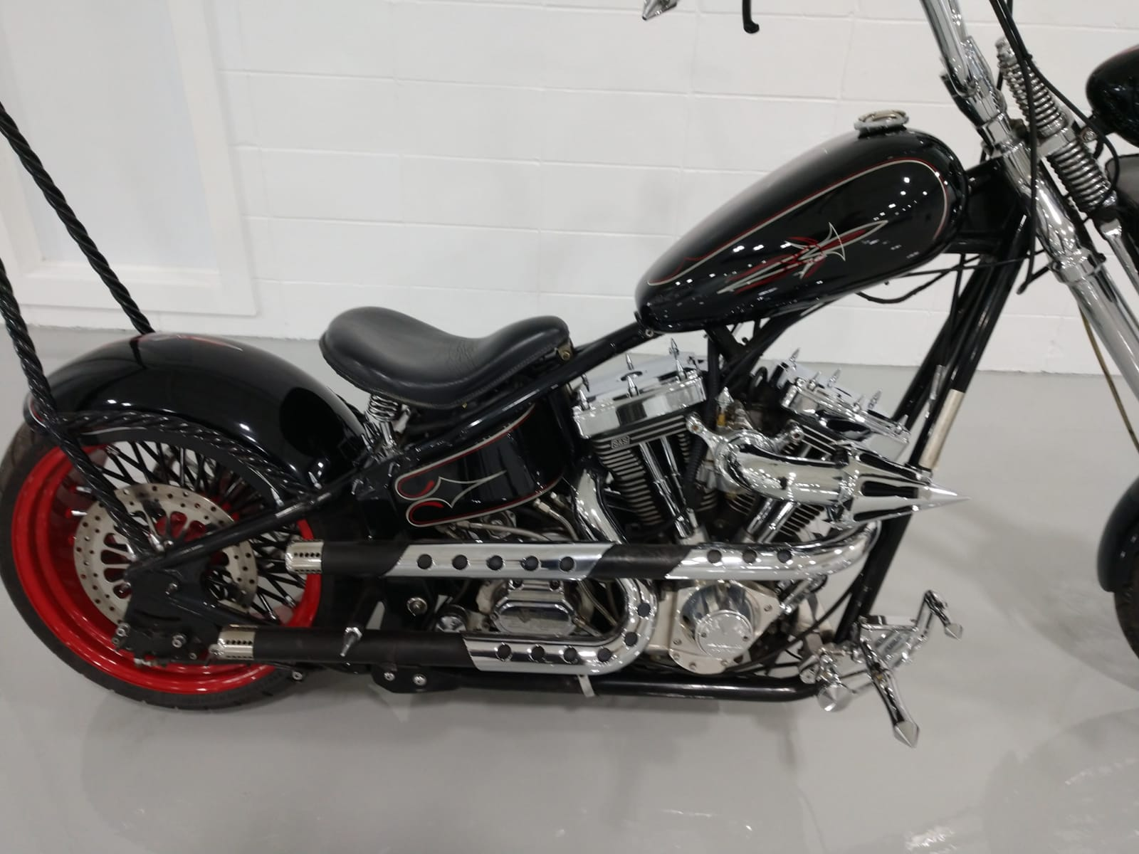 A black motorcycle with red wheels is parked in a garage