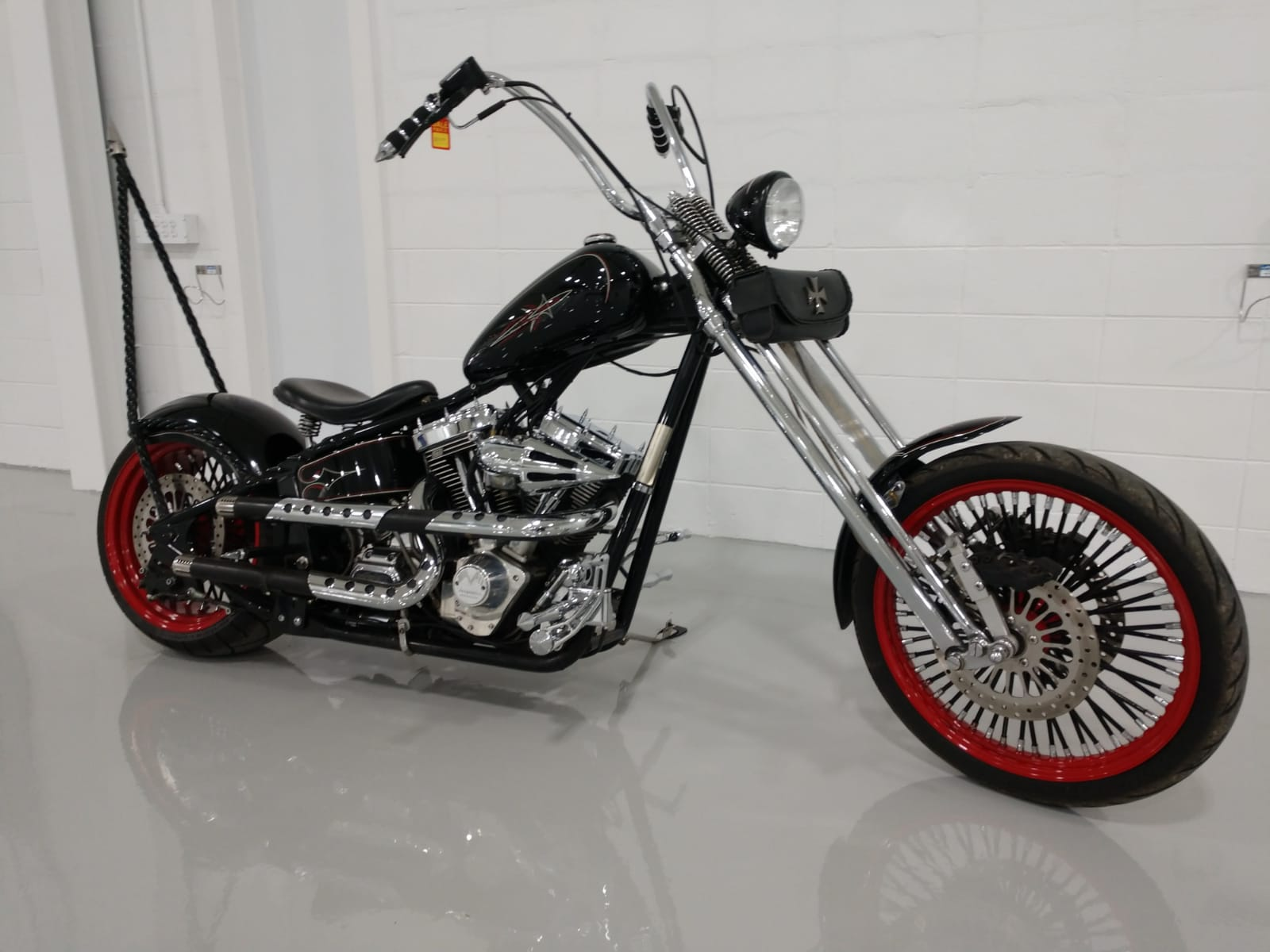 A black motorcycle with red wheels is parked in a garage