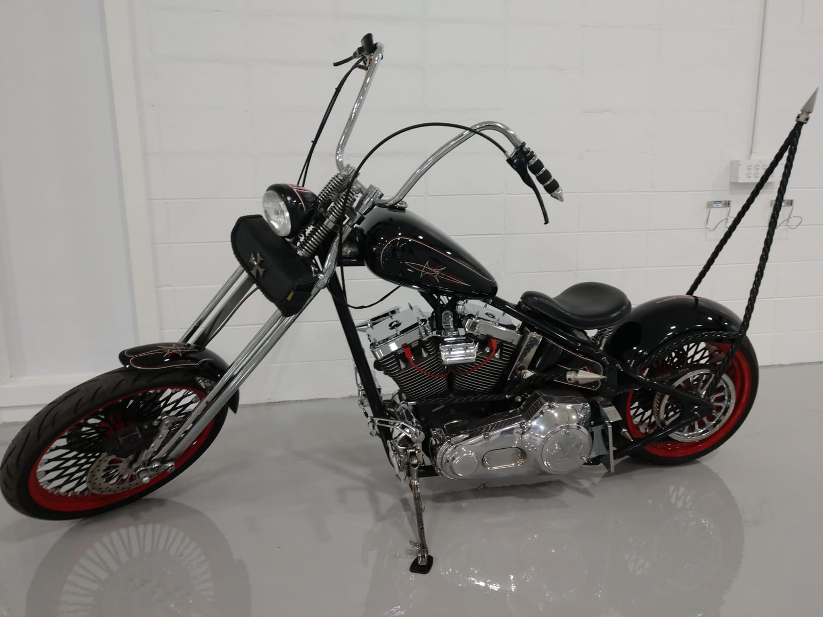 A black chopper motorcycle is parked in a garage