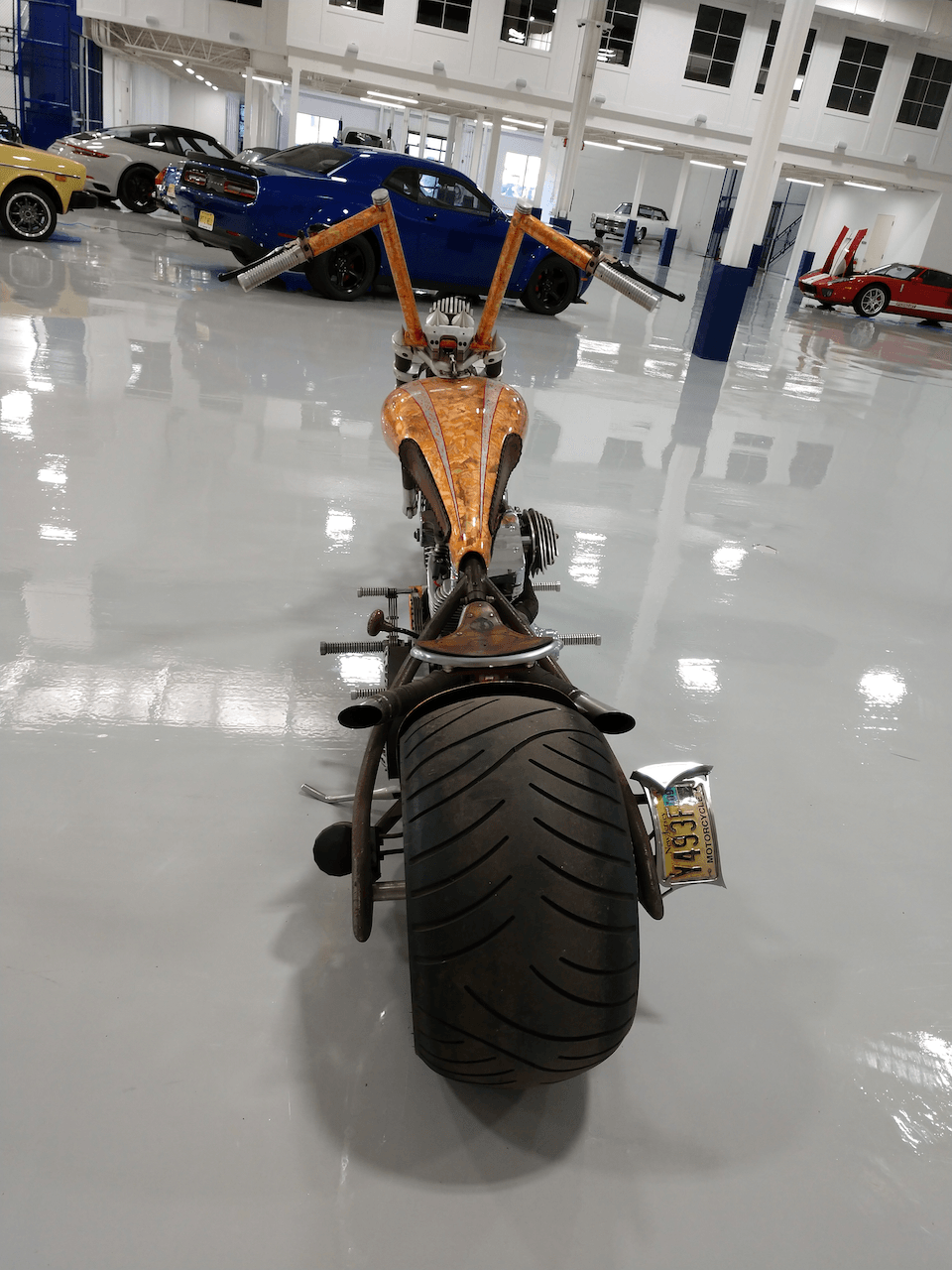 A motorcycle is parked in a garage with cars in the background.