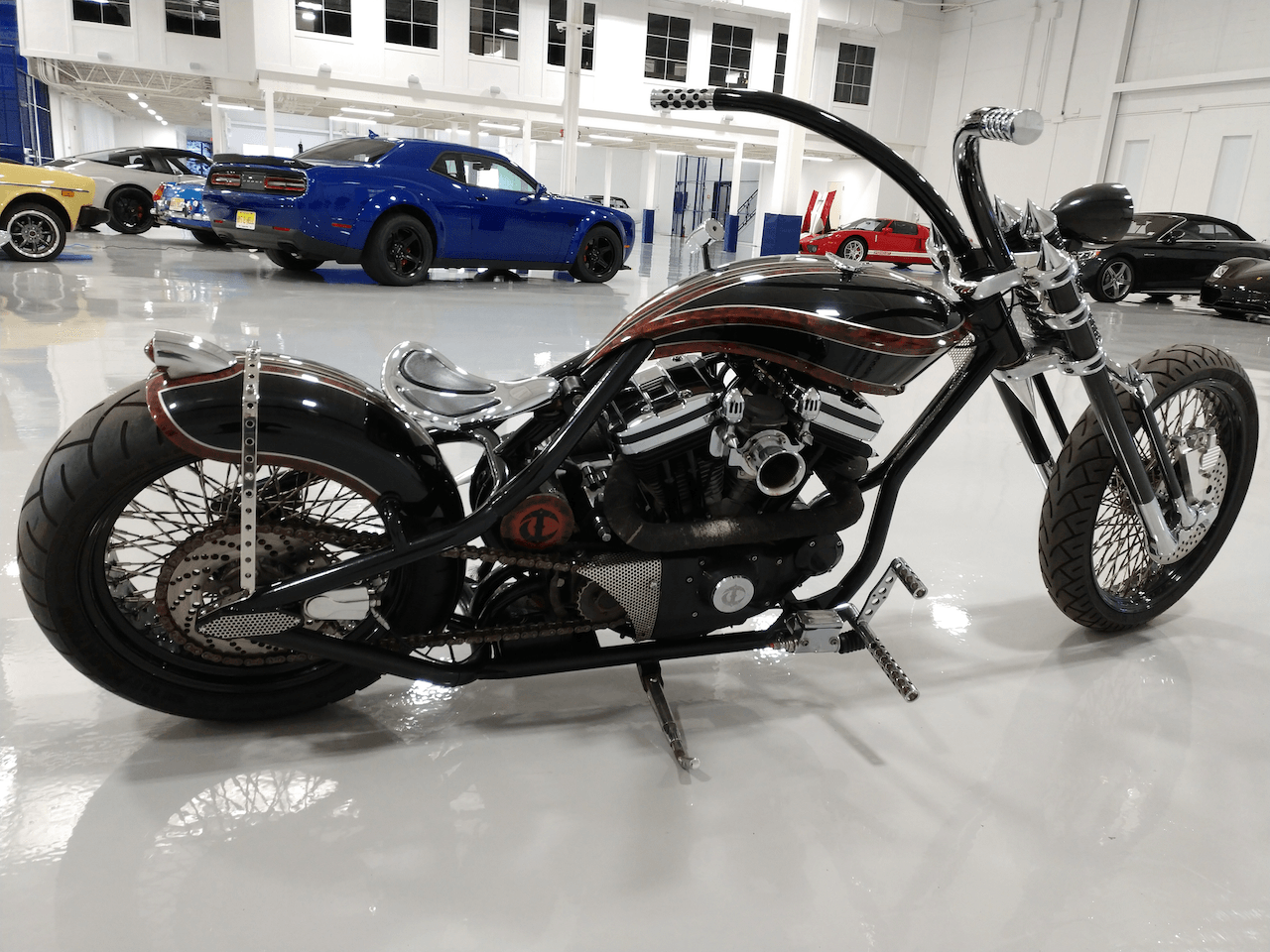 A motorcycle is parked in a garage with cars in the background.