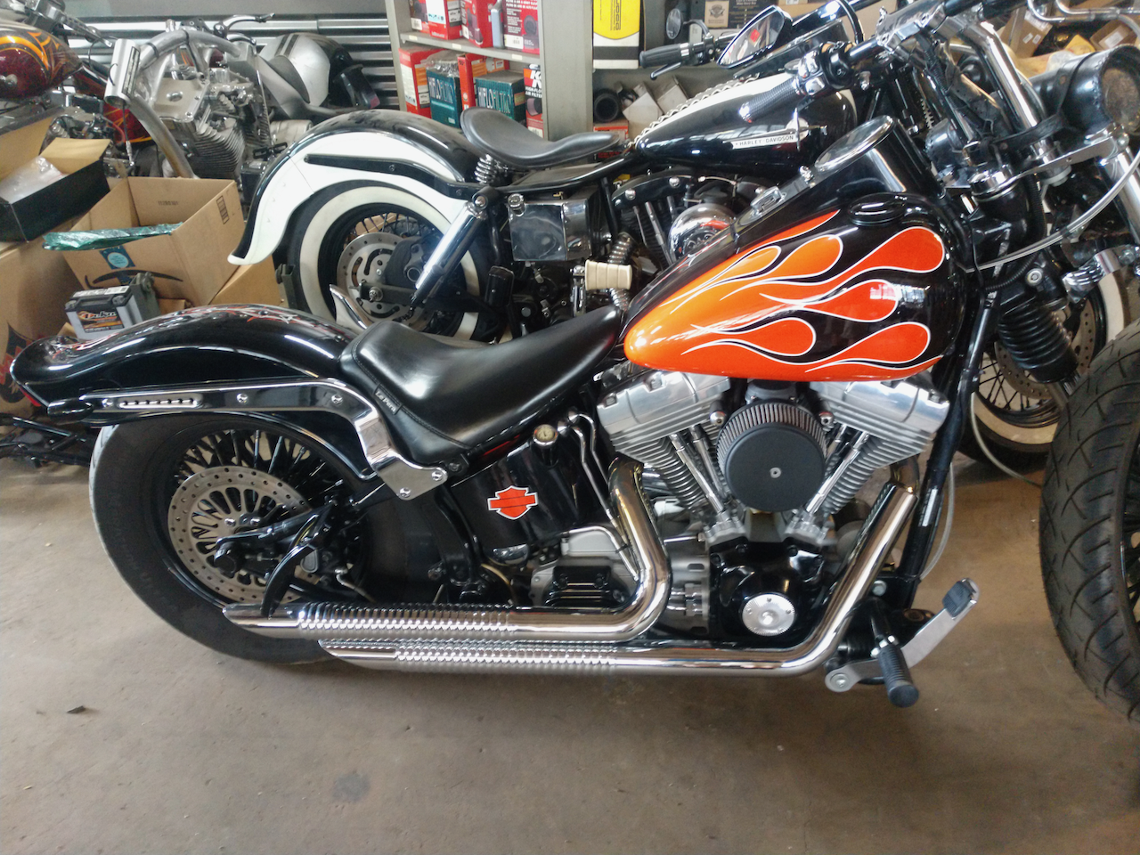A black and orange motorcycle with flames on the tank is parked in a garage