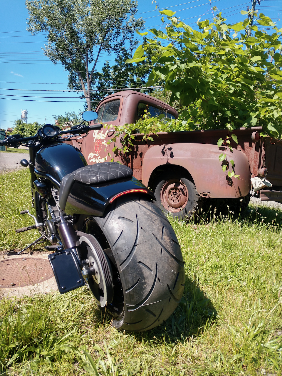 A motorcycle is parked in the grass next to an old truck.
