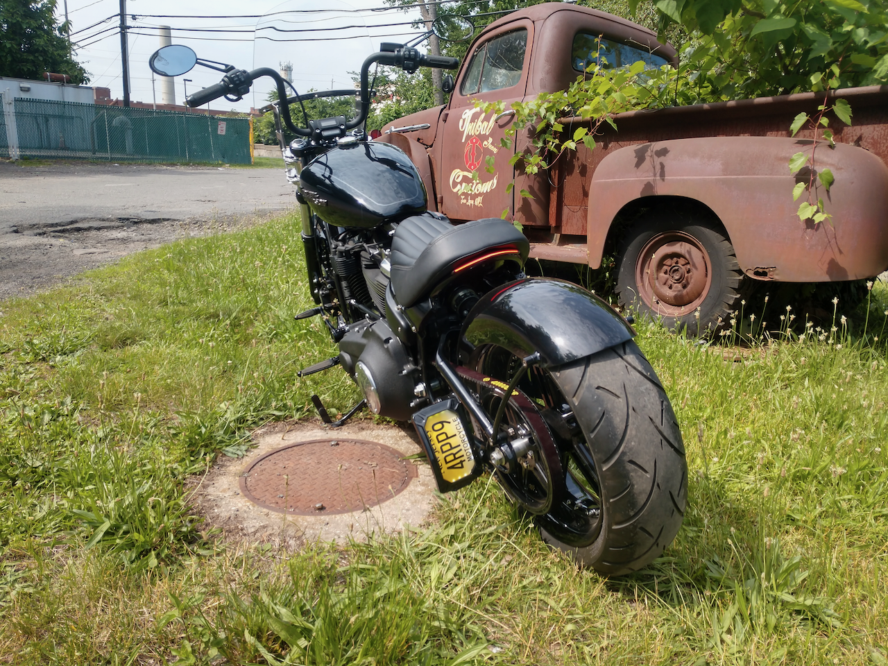 A motorcycle is parked in the grass next to an old rusty truck.