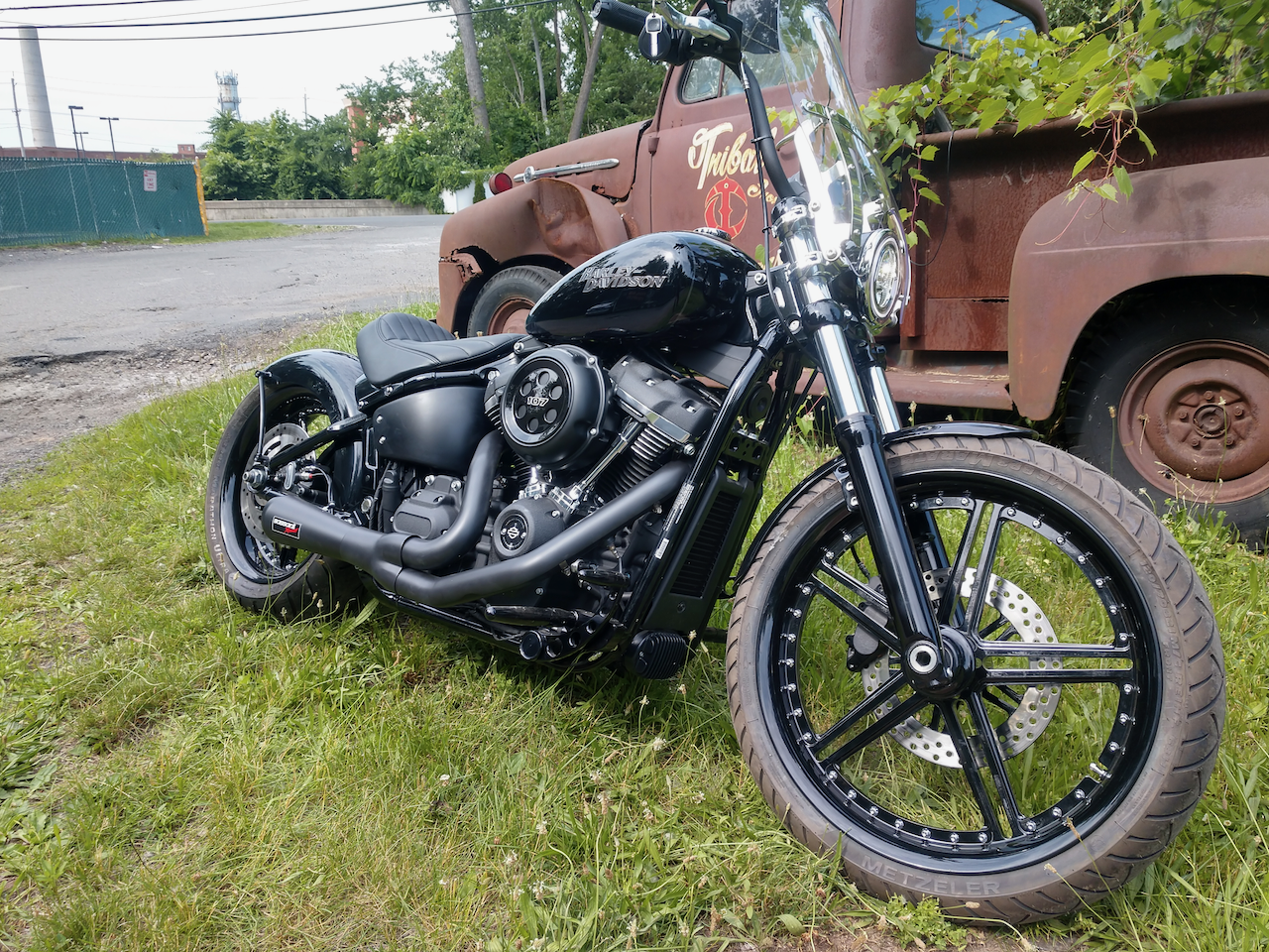 A black motorcycle is parked in the grass next to an old truck.