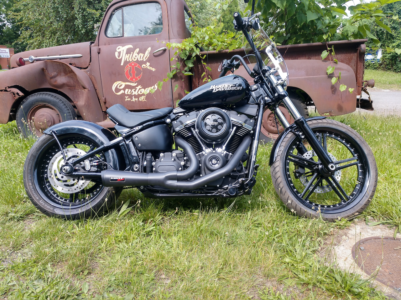 A motorcycle is parked in front of an old rusty truck.