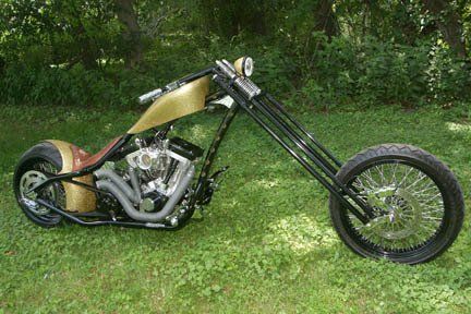 A chopper motorcycle is parked in the grass.