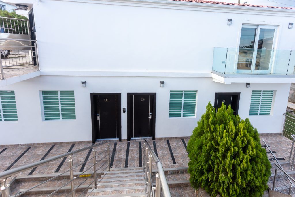 Lobby with brown sectional sofa, teal cushions, ottomans, artwork, and patterned rug.