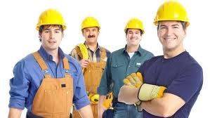A group of construction workers wearing hard hats and overalls are posing for a picture.