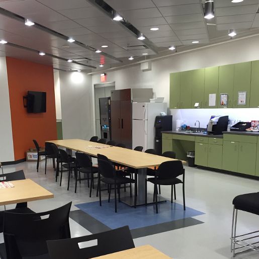 Large empty training room with grey and black striped floor, bright lights, and equipment along the wall.