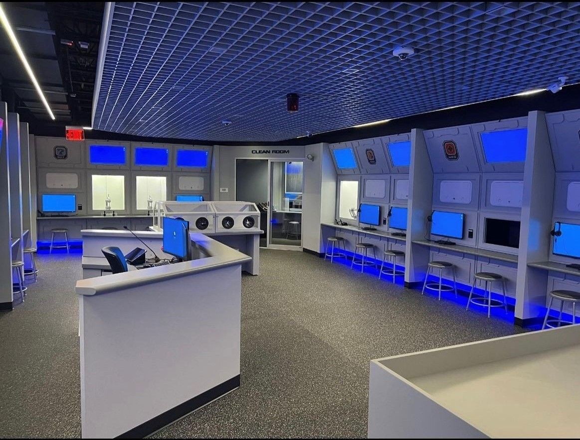 Modern office lobby with green accent wall, two planters, and a bench.