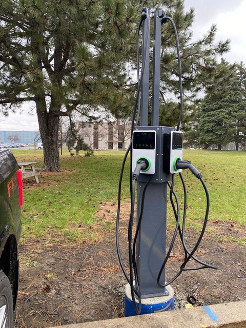 Electric vehicle charging station with two ports in a park setting.