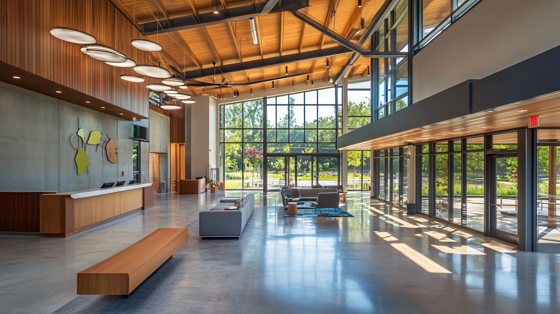 Lobby with wood and glass walls, concrete floors, and a view of trees.
