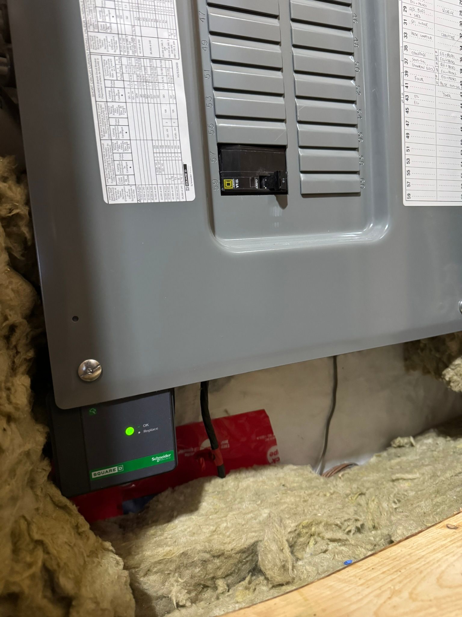 Gray electrical panel, green device, red cylinder, and insulation are visible.