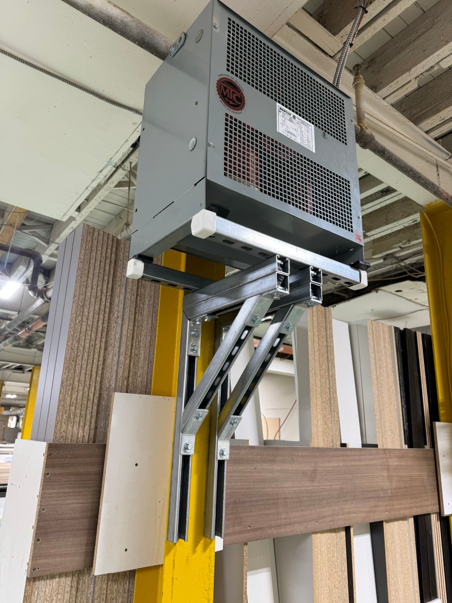 Gray industrial heater mounted on a scissor lift attached to a wall with wood samples.