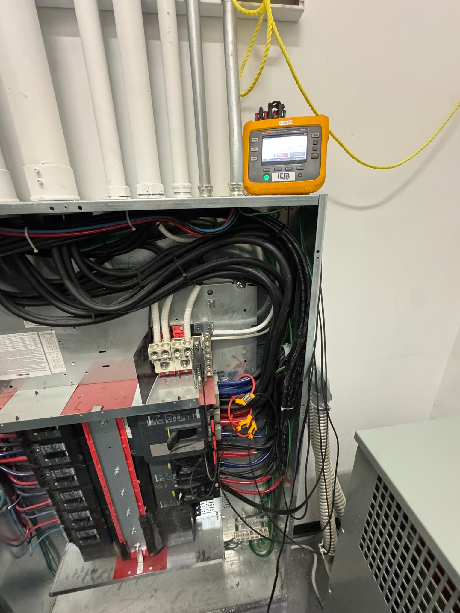 Electrical panel with wiring and a yellow testing device.