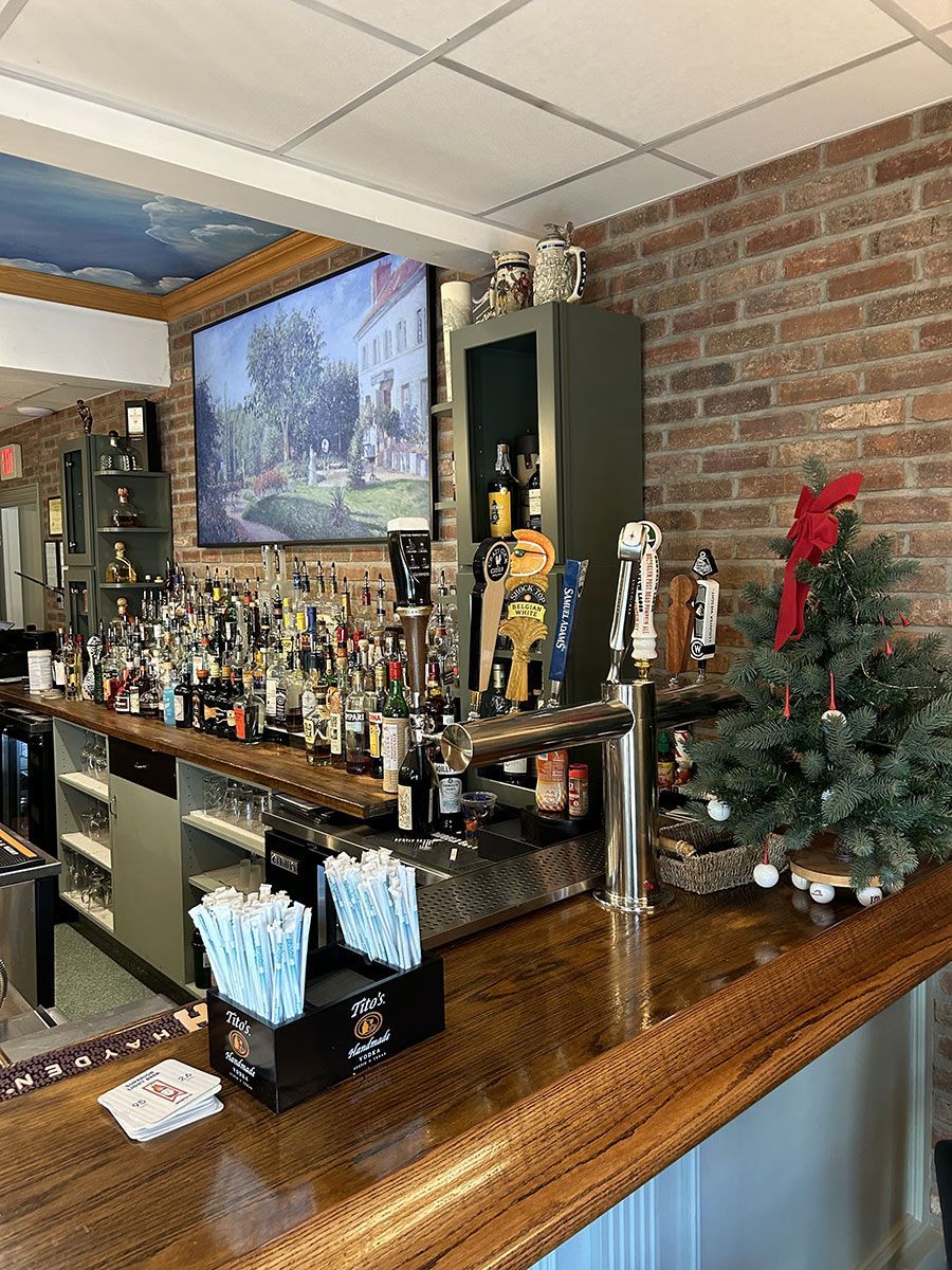 A bar filled with lots of bottles of liquor and a christmas tree.