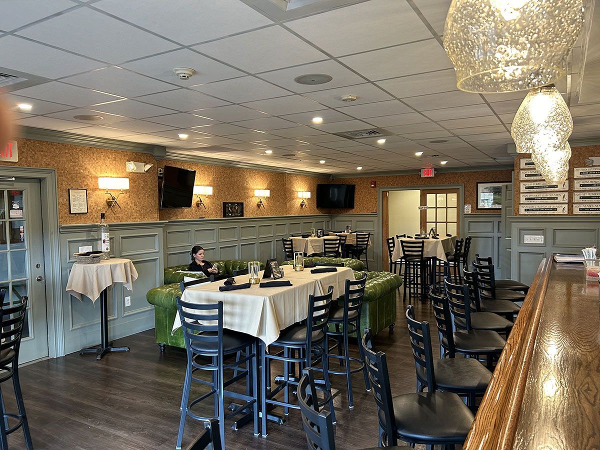 A large dining room with tables and chairs and a bar.