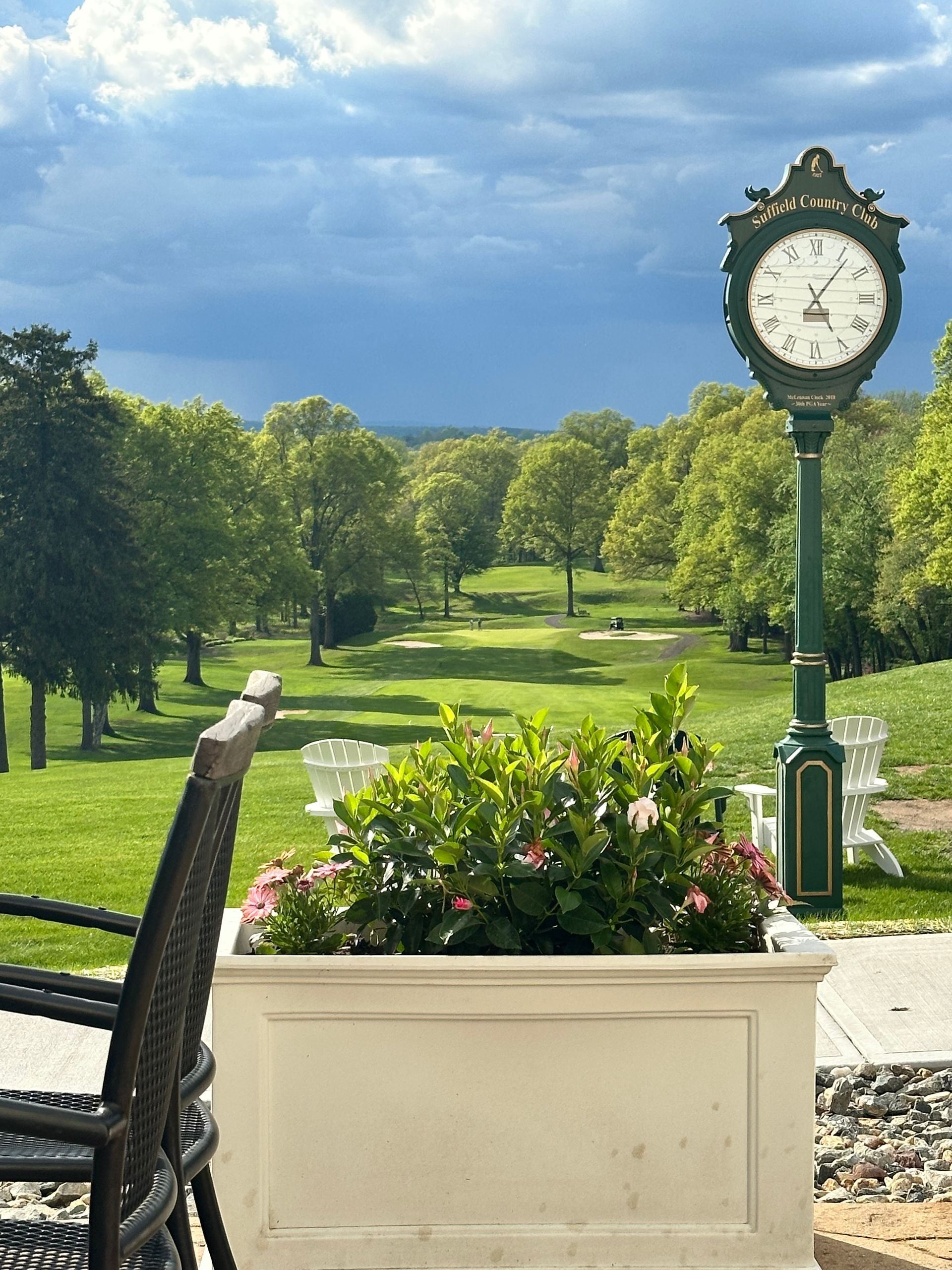 A clock on a pole in front of a golf course